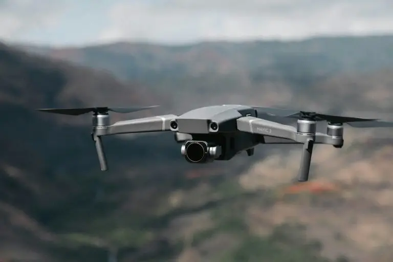 Sleek gray drone flying over blurred mountainous landscape. Sunlight reflects off the drone's metallic body, conveying high-tech innovation and adventure.